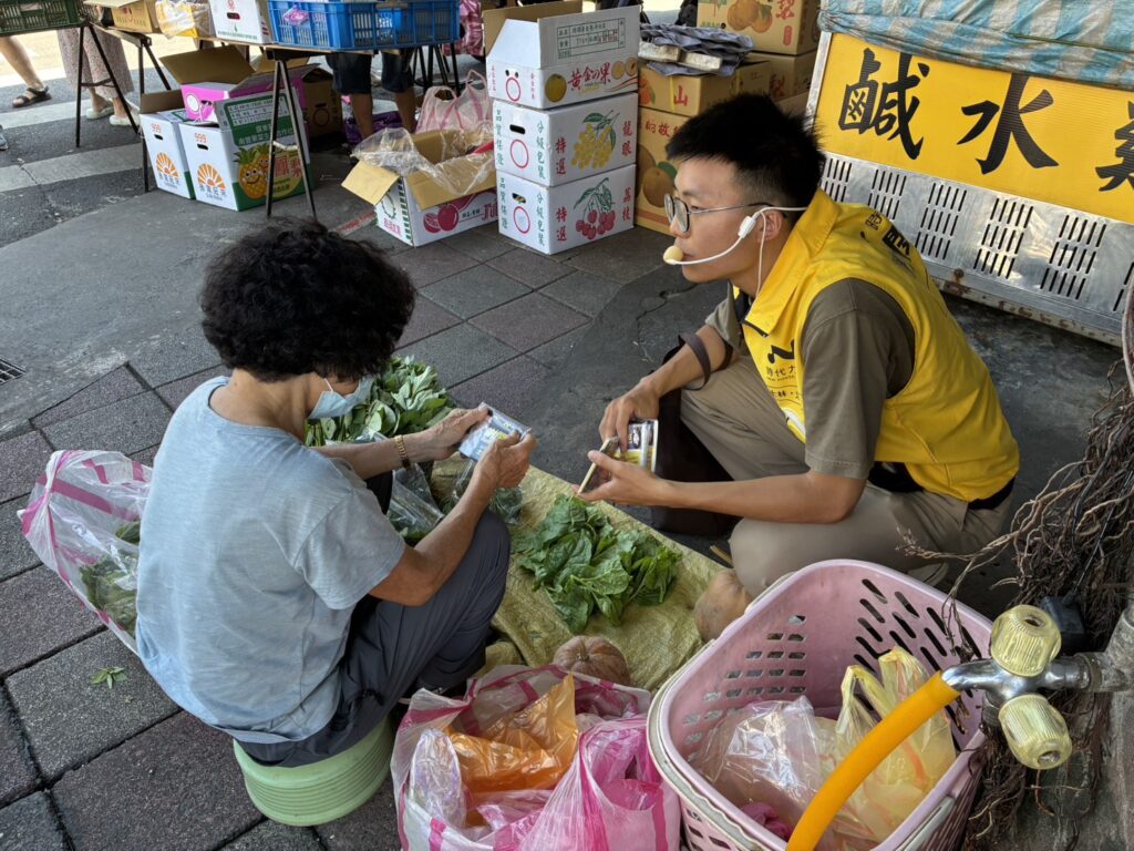 ▲在傳統市場裡,謝閔弘傾聽賣菜的年長市民對在地環境與生活協助上的細節,並分享他個人體會的經驗。(圖/謝閔弘團隊 提供)