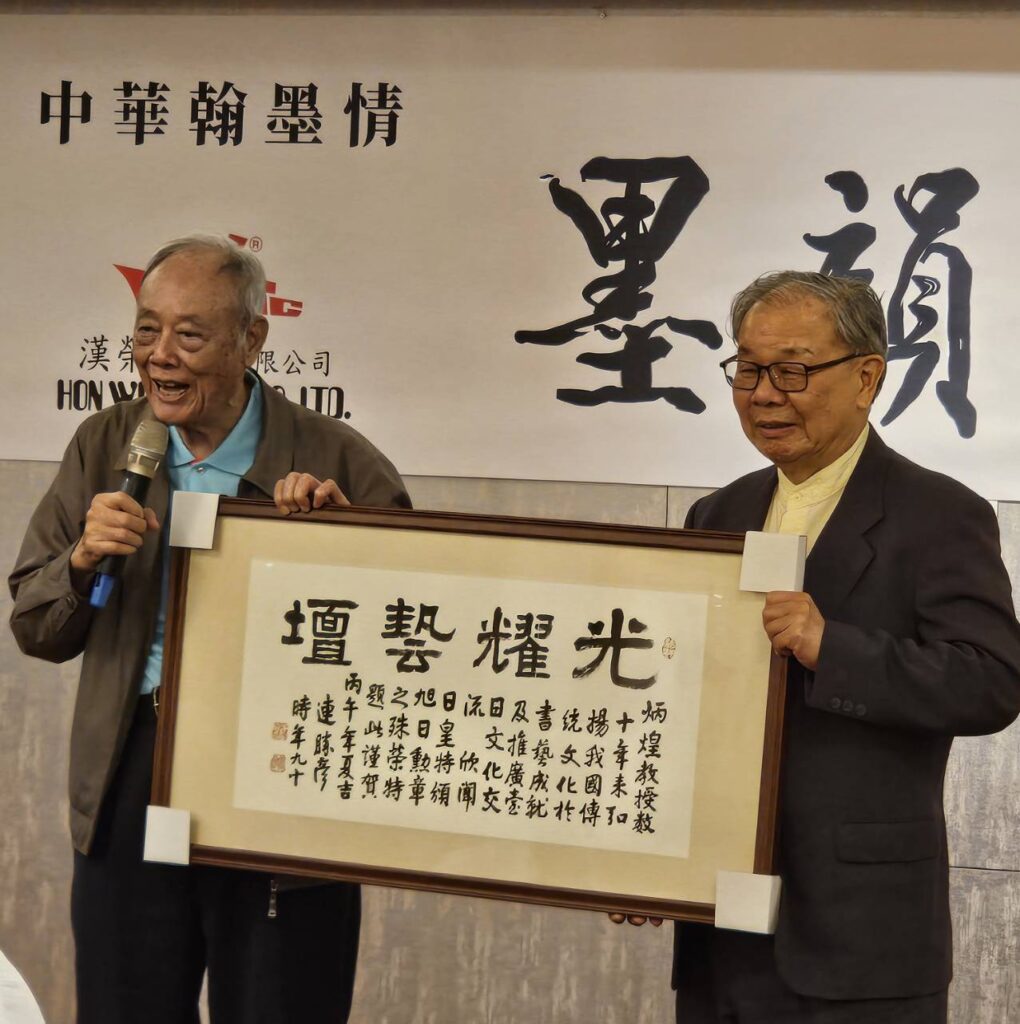 ▲書法界大師連勝彥董事長(左)特別推崇張炳煌教授榮獲日本政府所頒贈授予的勳章,認為是臺灣書法界的榮耀,他特別書寫「光耀藝壇」墨寶贈送,成為全場矚目焦點。(記者 辛澎祥/攝)